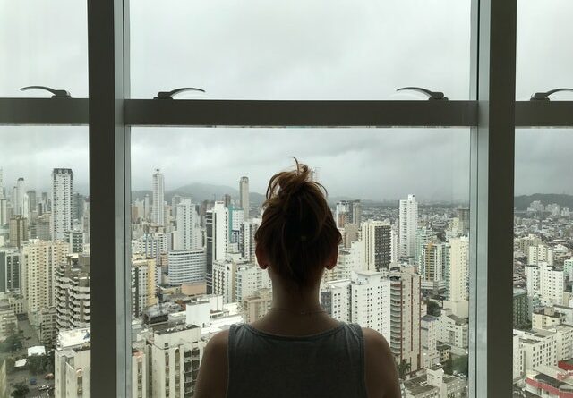 Kobieta stoi przy oknie które ma szkło na wymiar