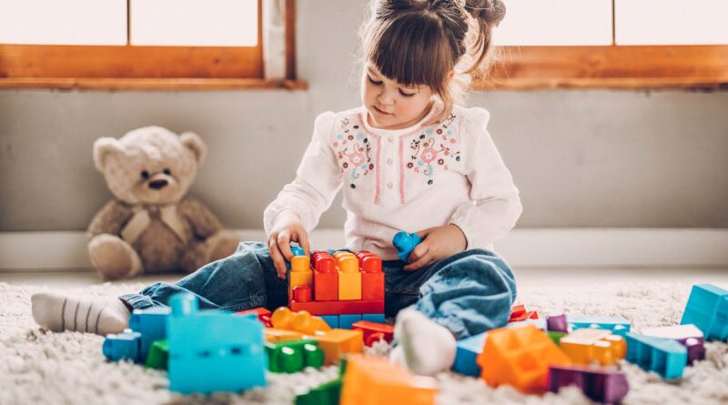mała dziewczynka bawi się zabawkami które wspomagają jej rozwój